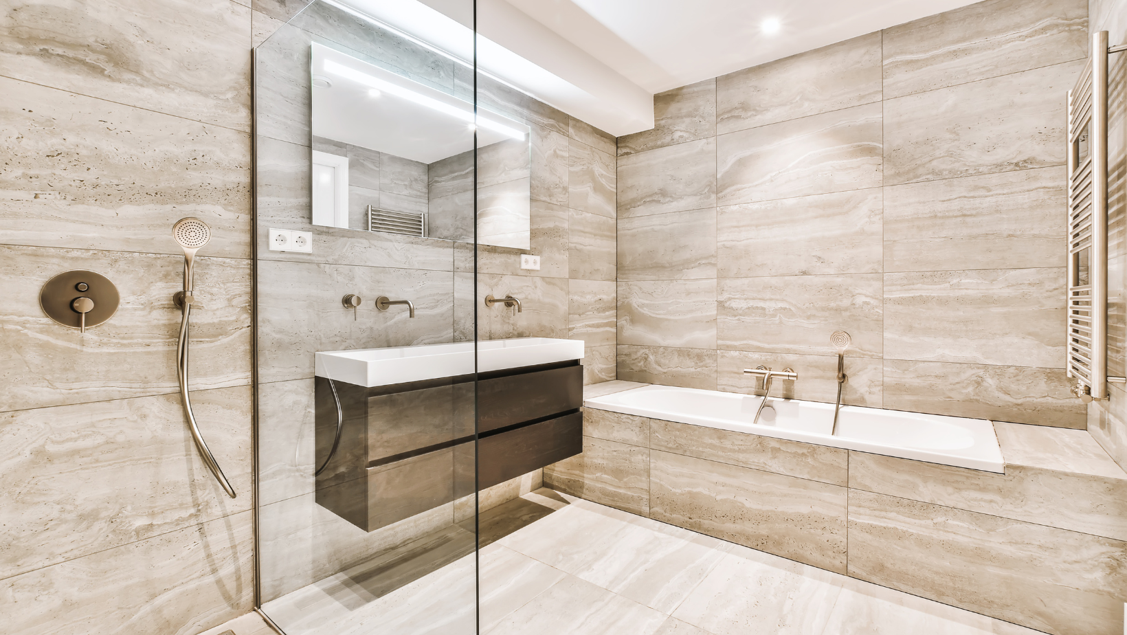 Modern beige marble bathroom with glass shower, floating vanity, and bathtub beside a window