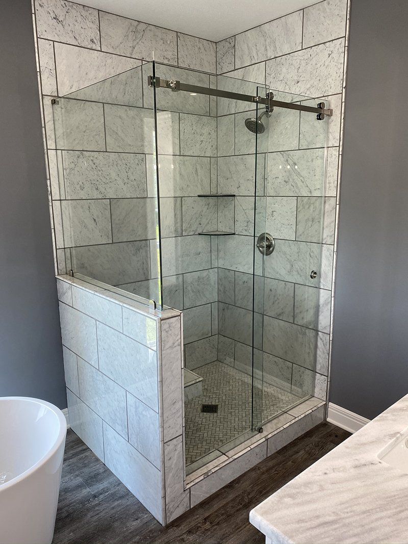 Glass corner shower with tiled walls and a partial tile pony wall in a bathroom