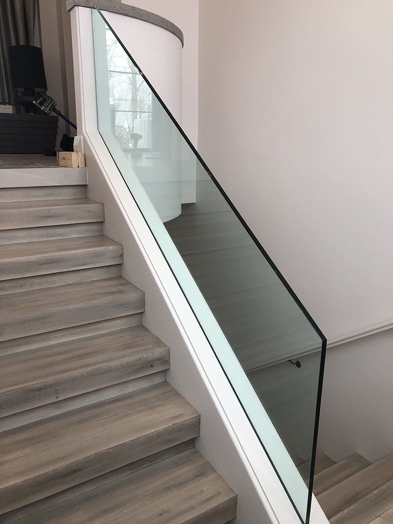 Staircase with glass railing and white walls in a modern interior