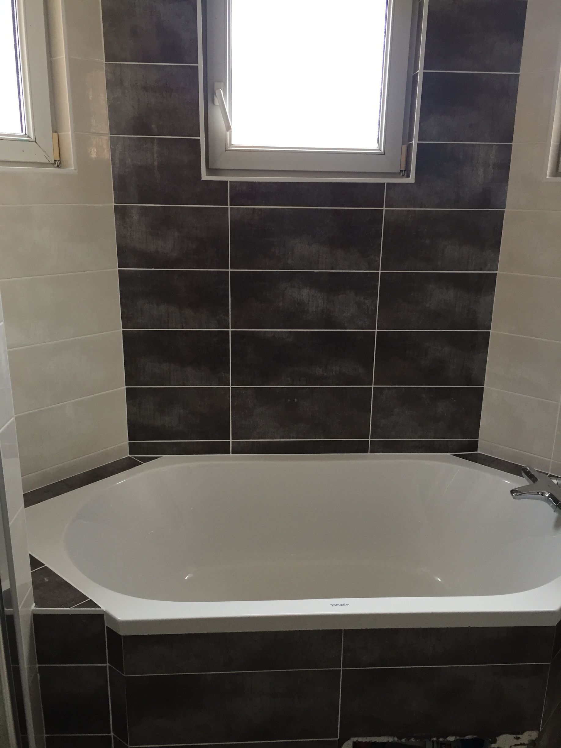 Après : baignoire d'angle blanche et carrelage anthracite effet béton, salle de bain rénovée à Gambsheim