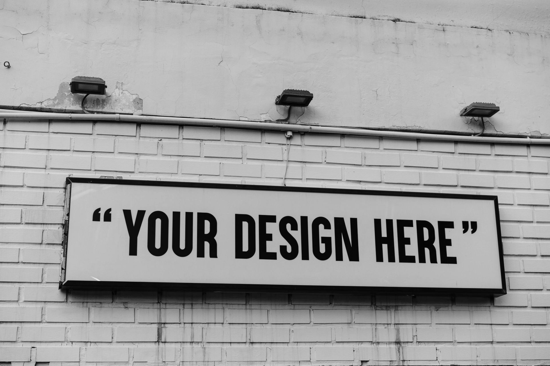 A rectangular sign on a white brick wall that reads