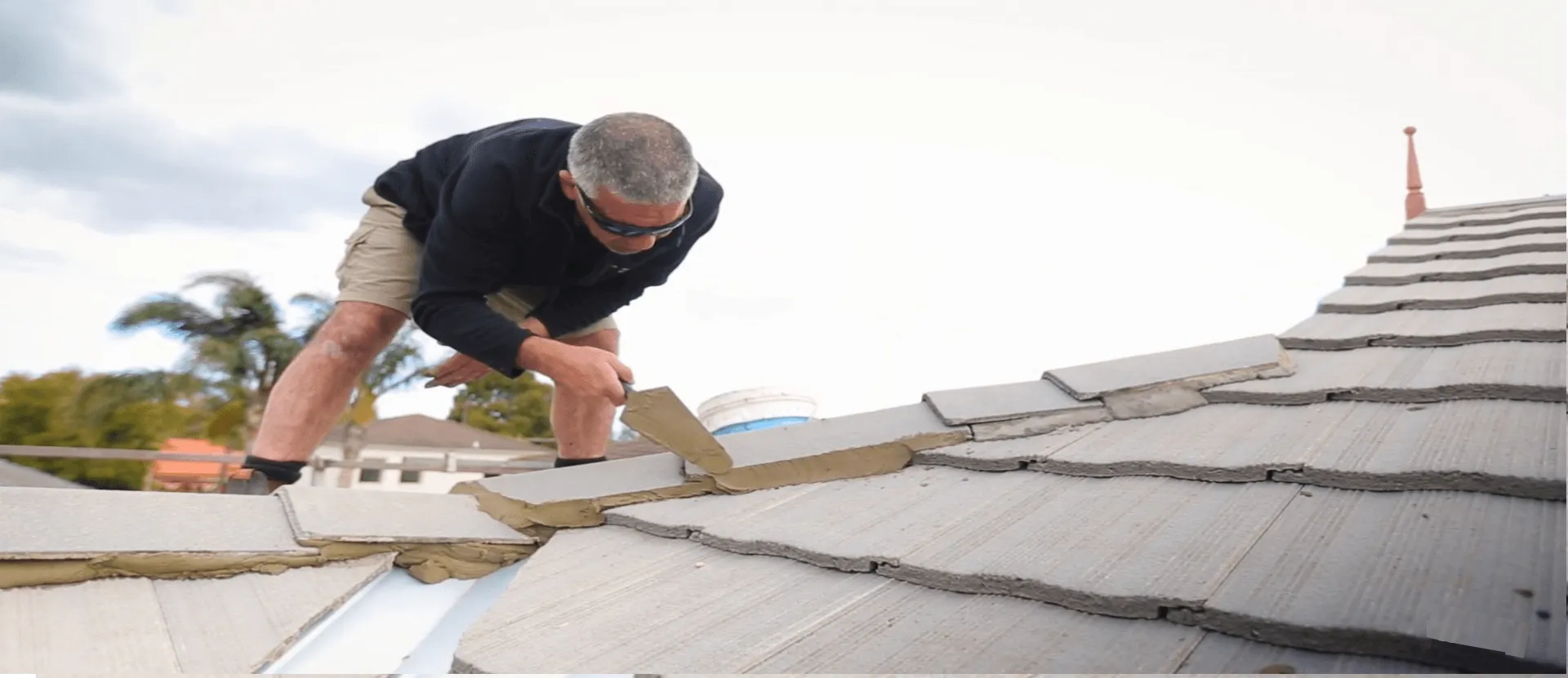 a man is working on a roof restoration with a trowel