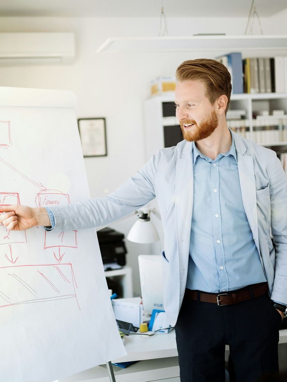 A man is pointing at a diagram on a whiteboard.