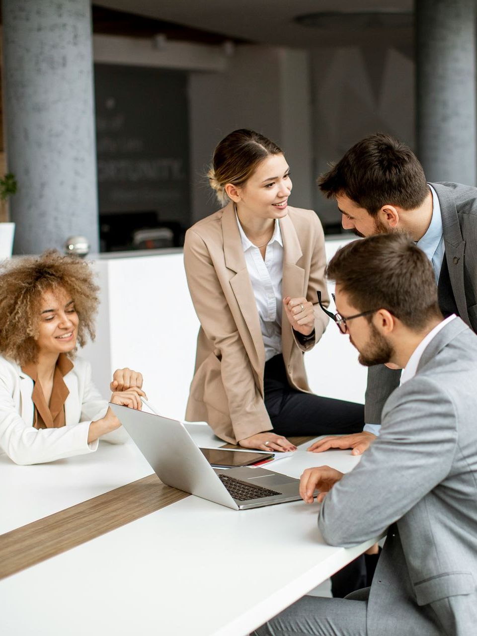 A group of business people are sitting around a table with laptops.