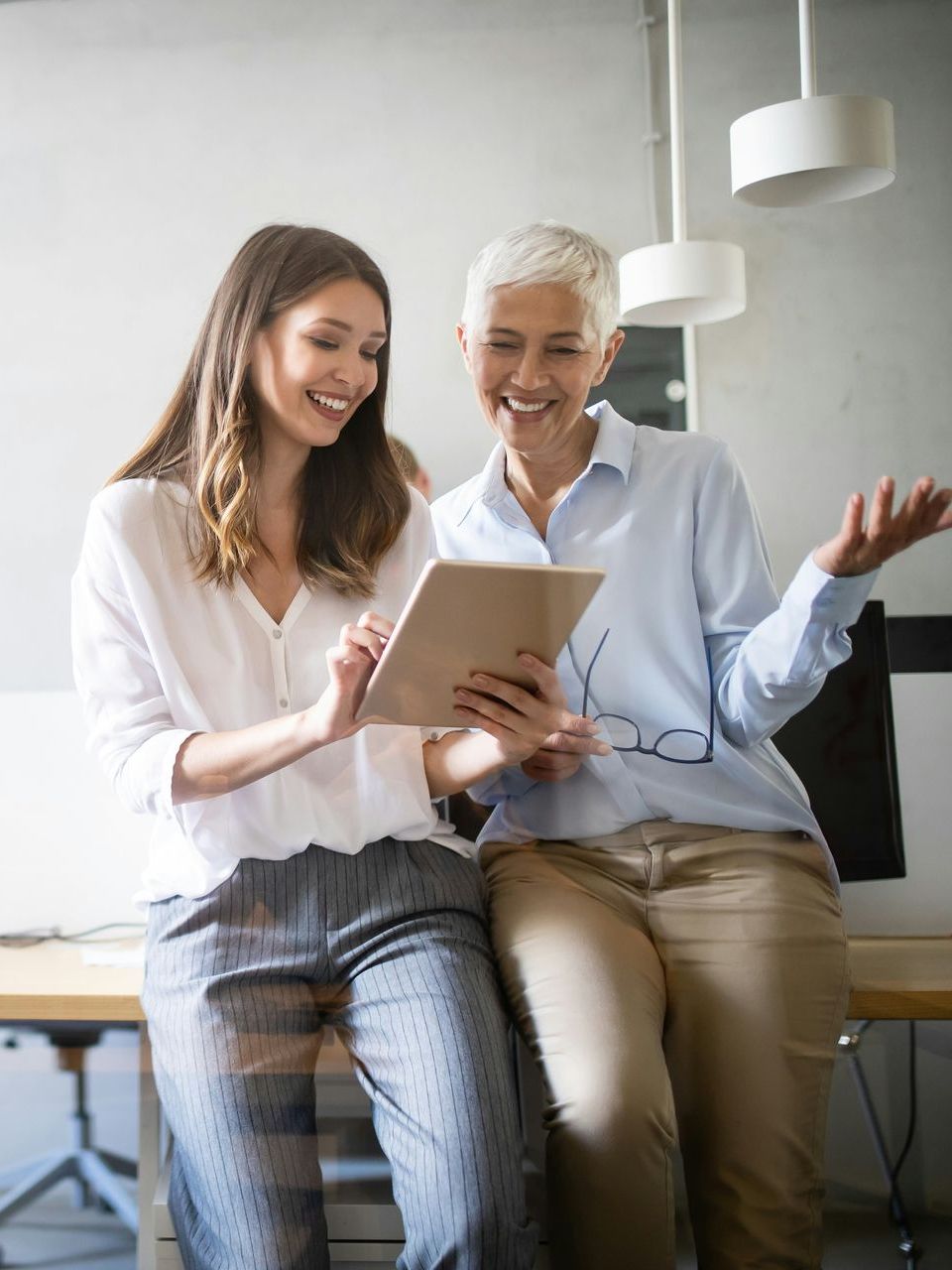 Two women are sitting next to each other looking at a tablet.