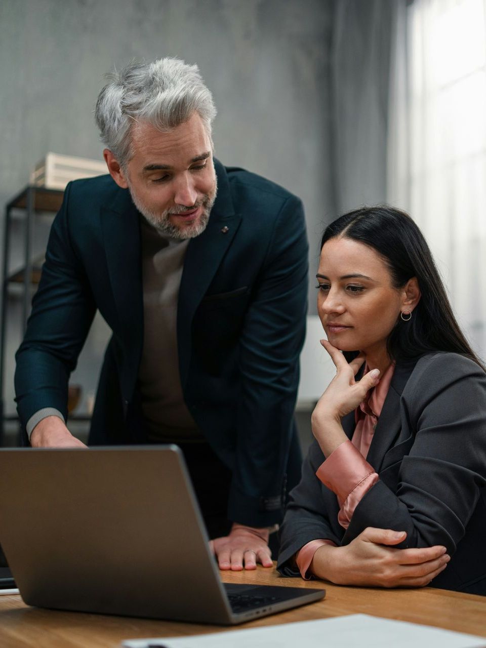 A man and a woman are looking at a laptop computer.