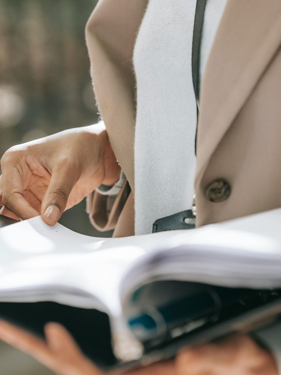 A person is holding a book and a cell phone in their hands.