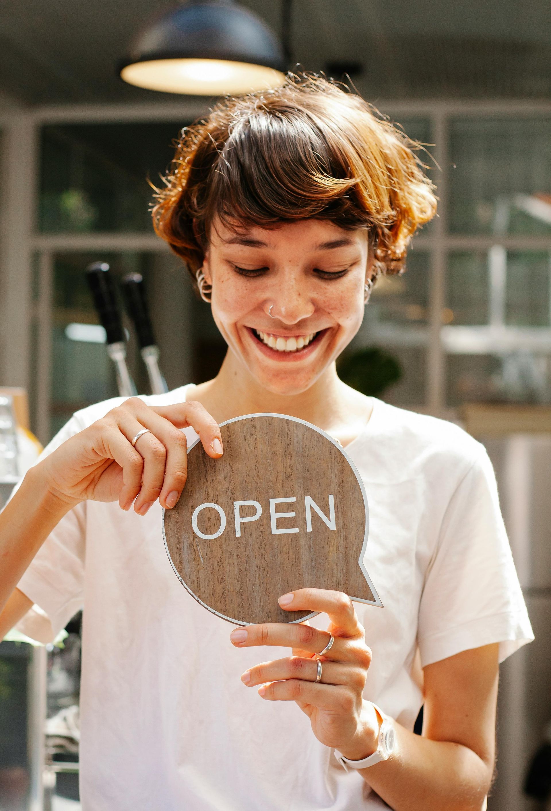 A woman is holding a sign that says `` open ''.