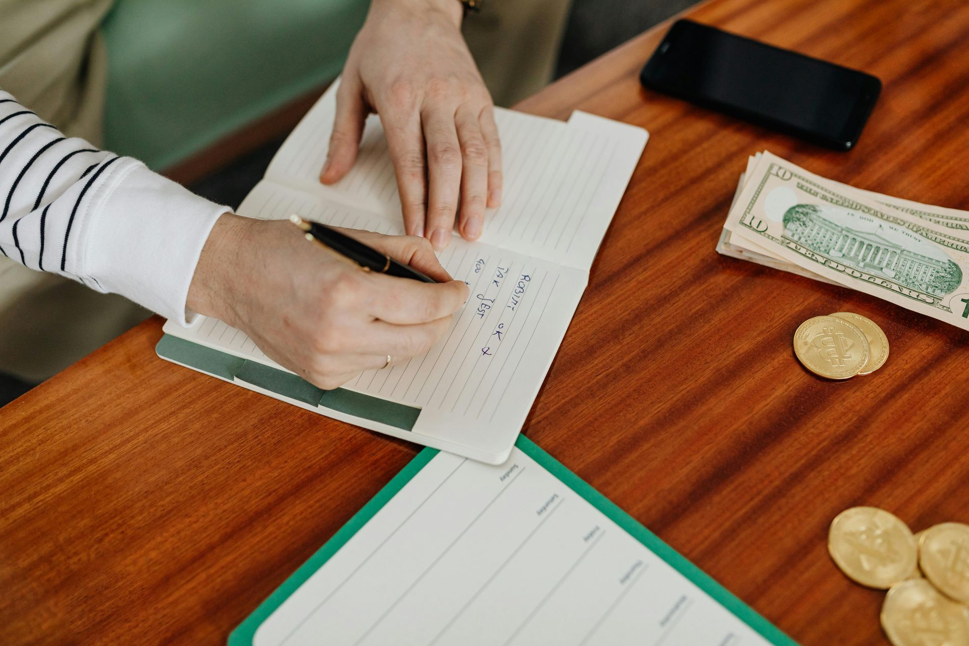 A person is sitting at a table writing in a notebook.