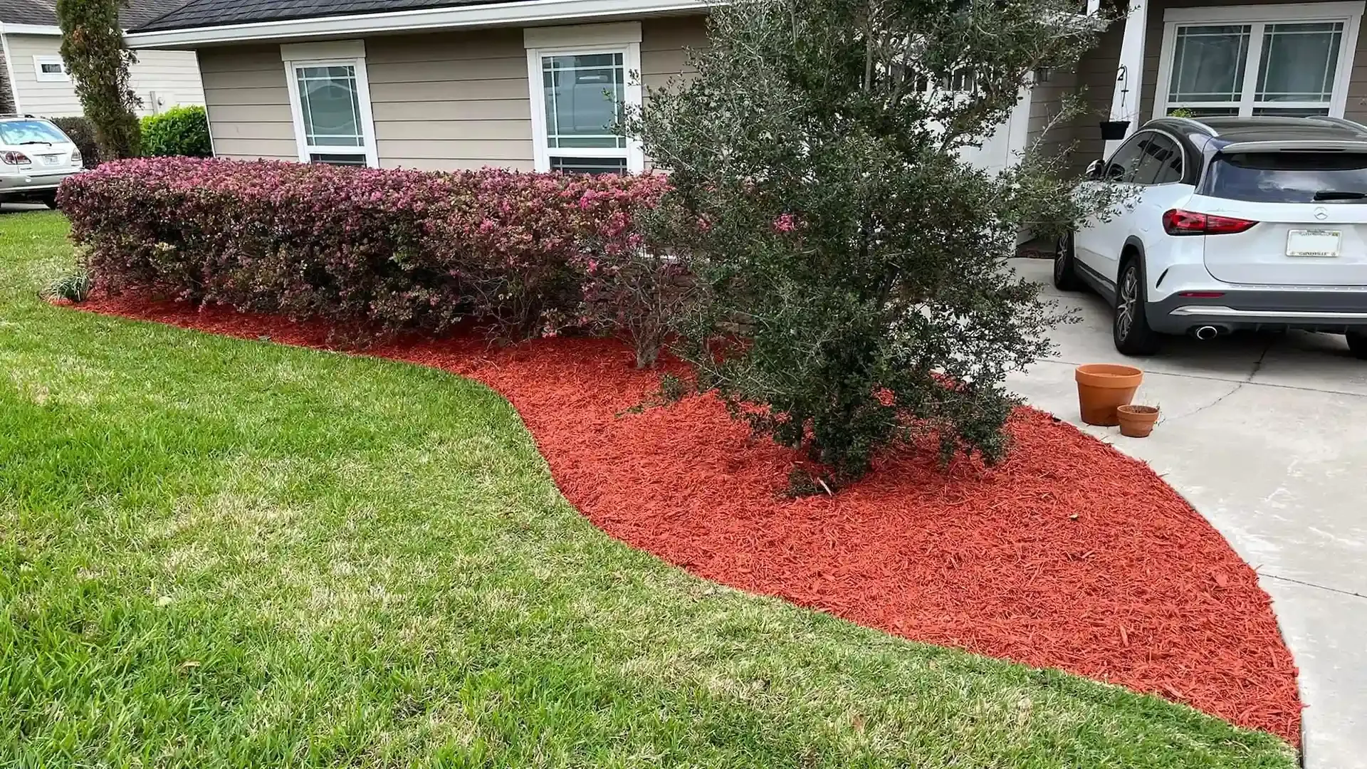 A green lawn next to a house with red mulch in the yard.