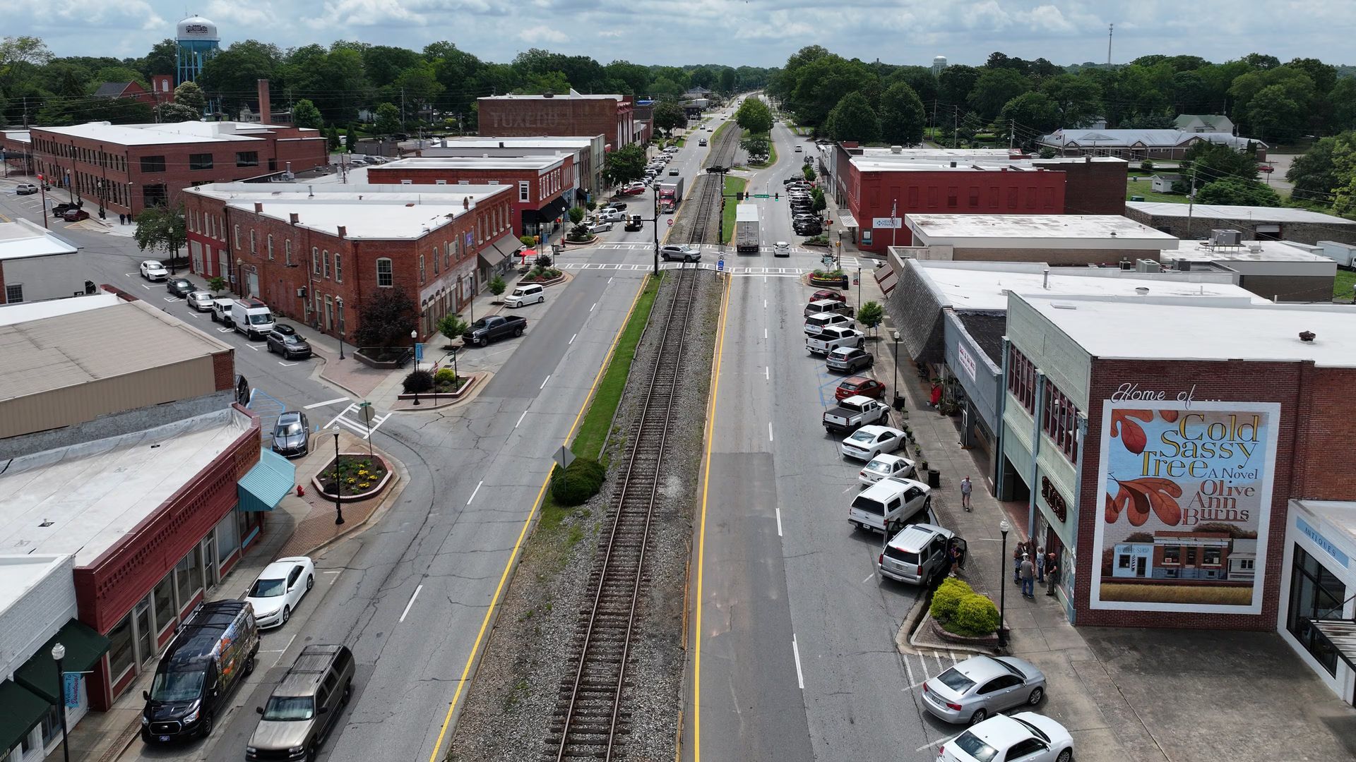 Aerial view of a downtown street with train tracks down the middle, buildings on either side, and parked cars.