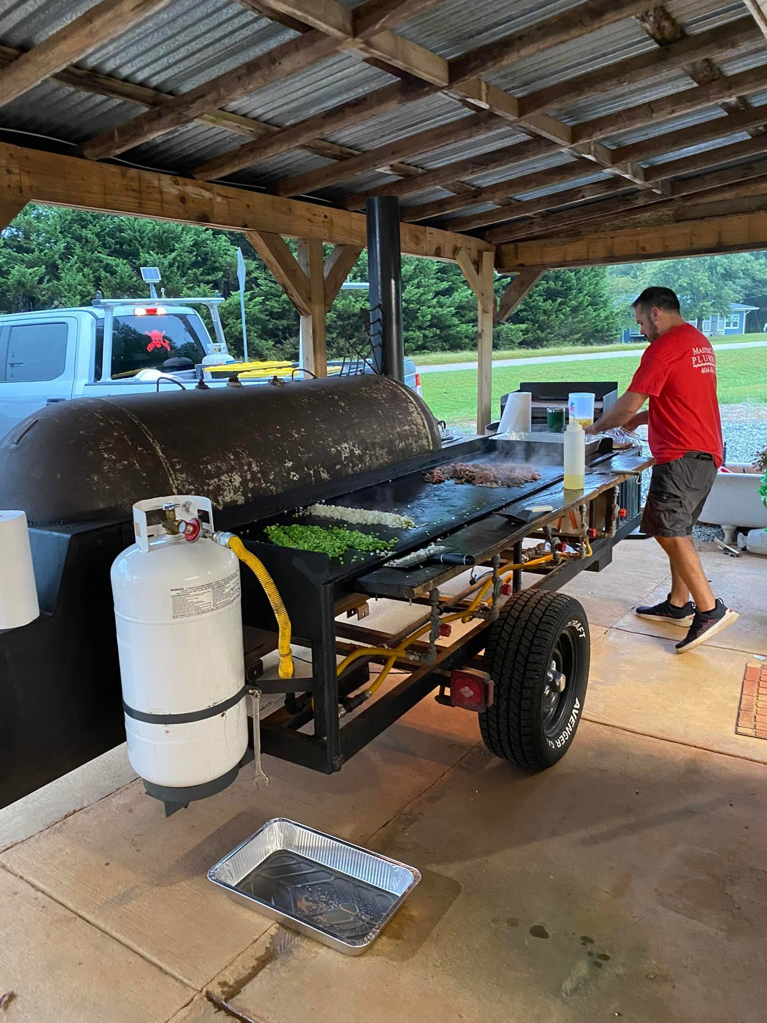 MasterCraft Plumbing charity event with food and man grilling in MasterCraft Plumbing red shirt
