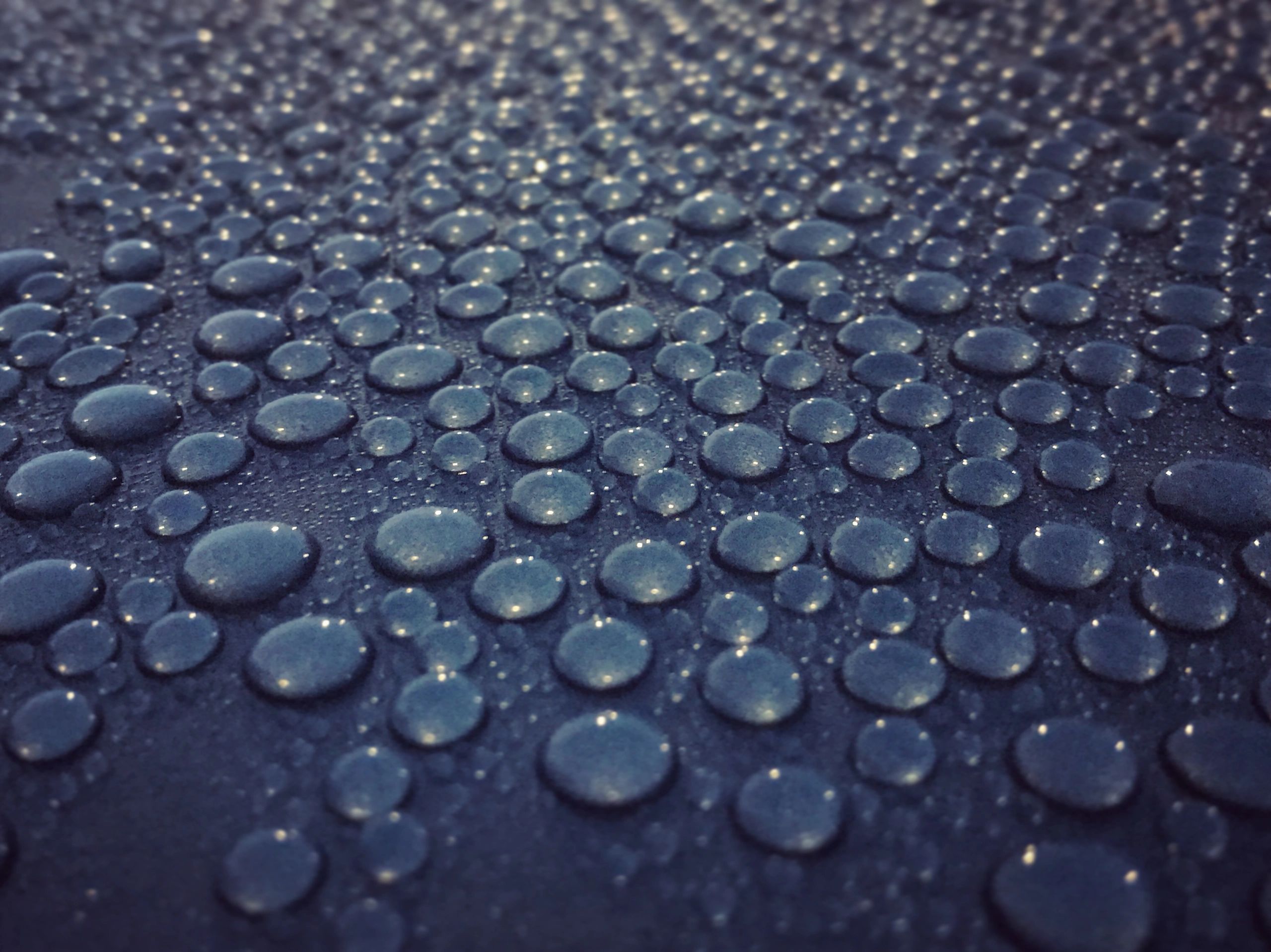 A close up of water drops on a black surface.
