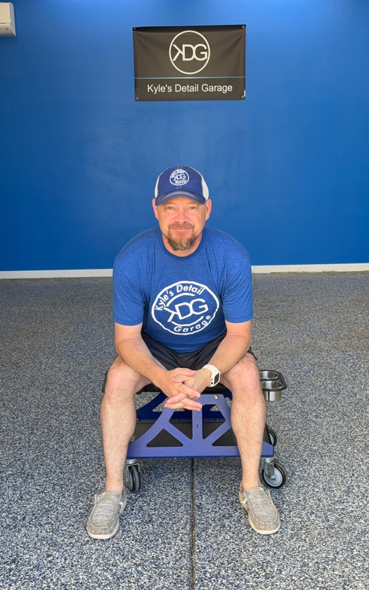 A man is standing in front of a blue truck.