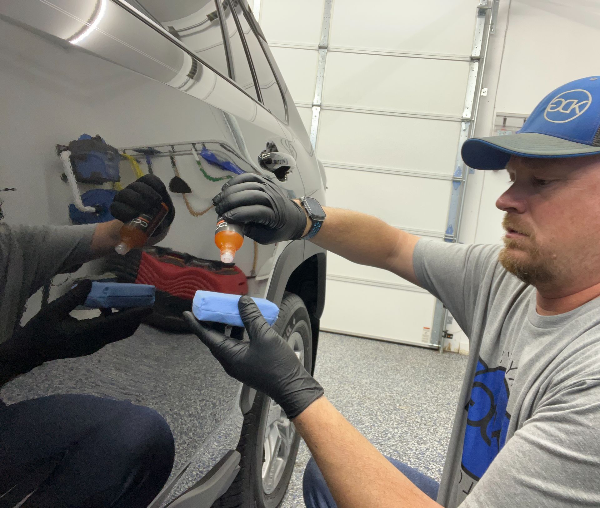 a person wearing black gloves is cleaning a car headlight