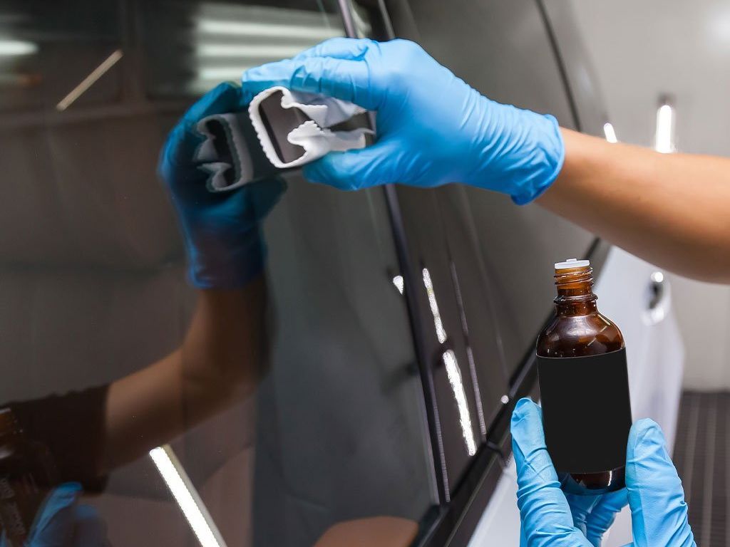 A person wearing blue gloves is polishing a car.