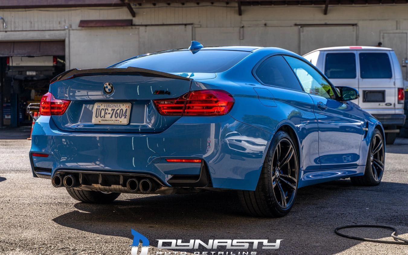 A blue bmw m4 is parked in a parking lot in front of a building.