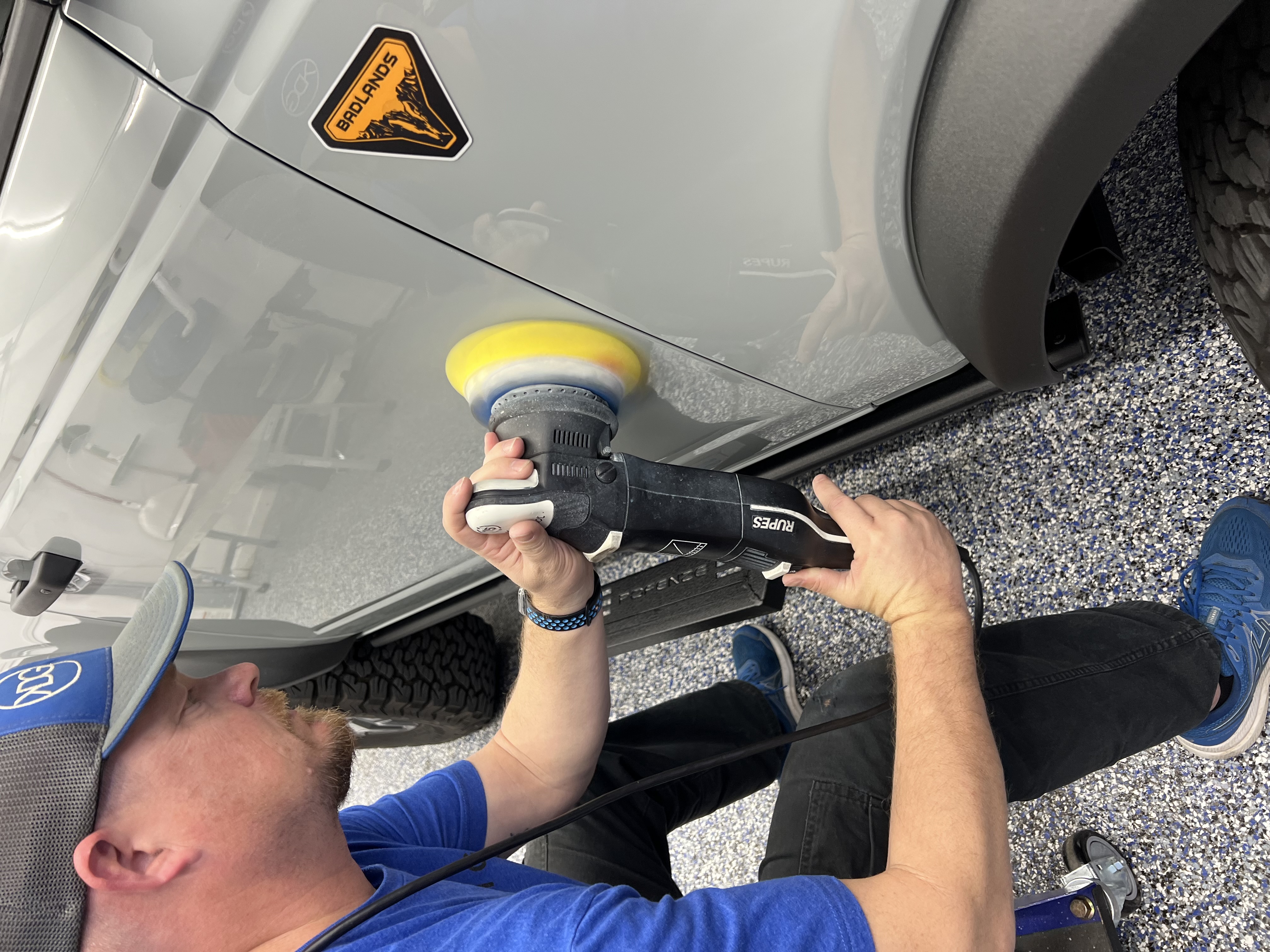 a man wearing black gloves is polishing a white car