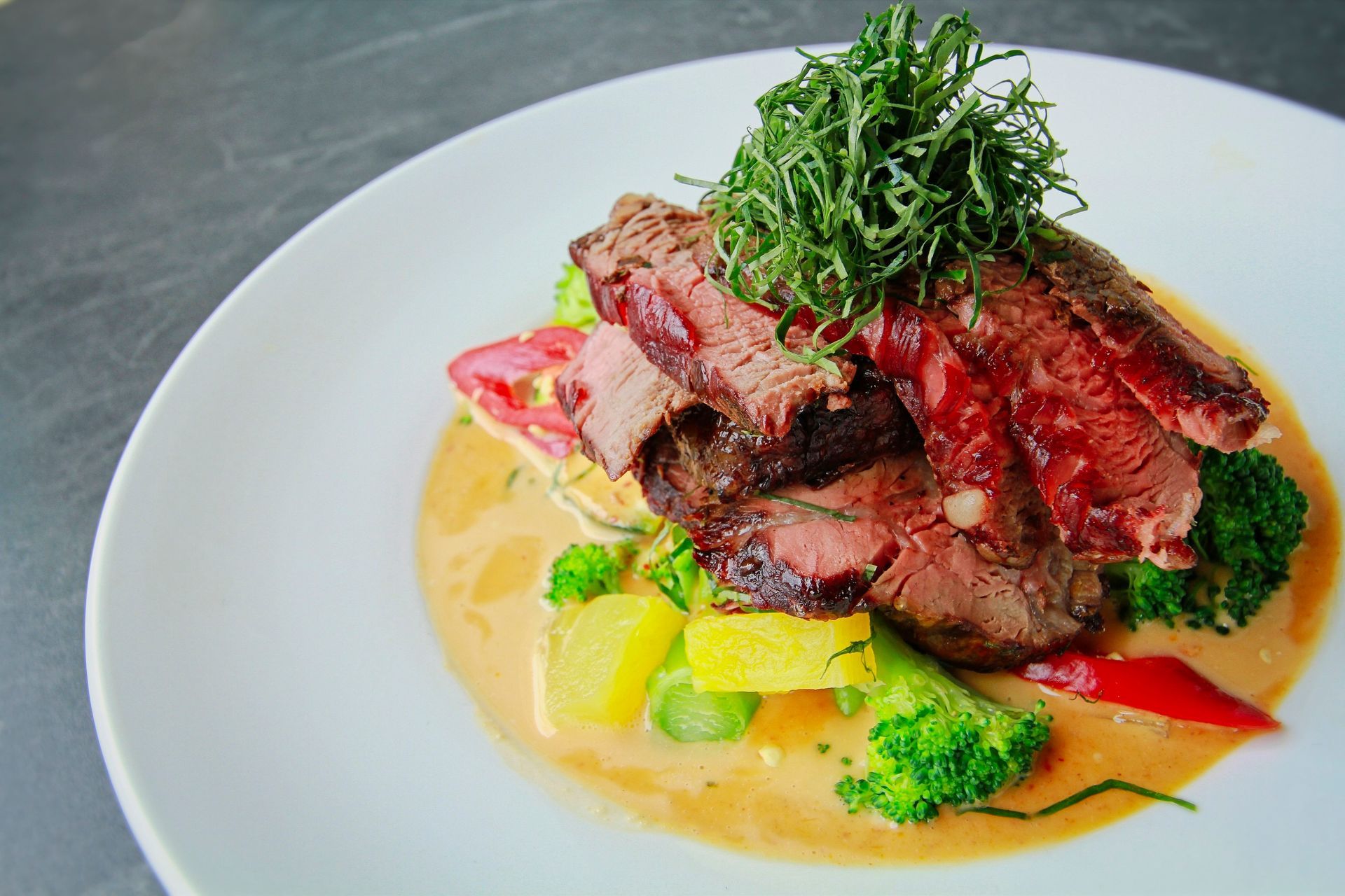 Sliced beef in red curry sauce with broccoli and crispy herbs