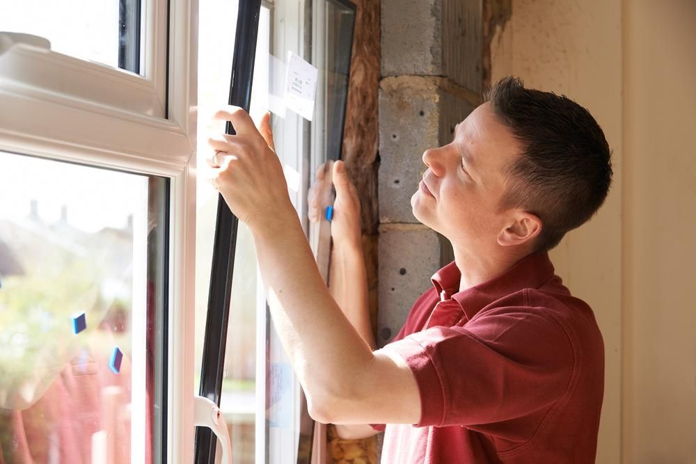 A Man in a Red Shirt is Installing a Window — Headlands Glass in Bangalow, NSW