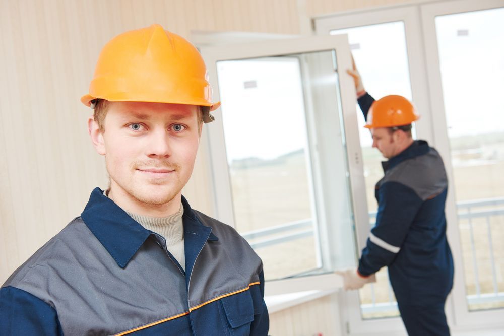 A Man Wearing An Orange Hard Hat Is Standing In Front Of A Window — Headlands Glass in Byron Bay, NSW