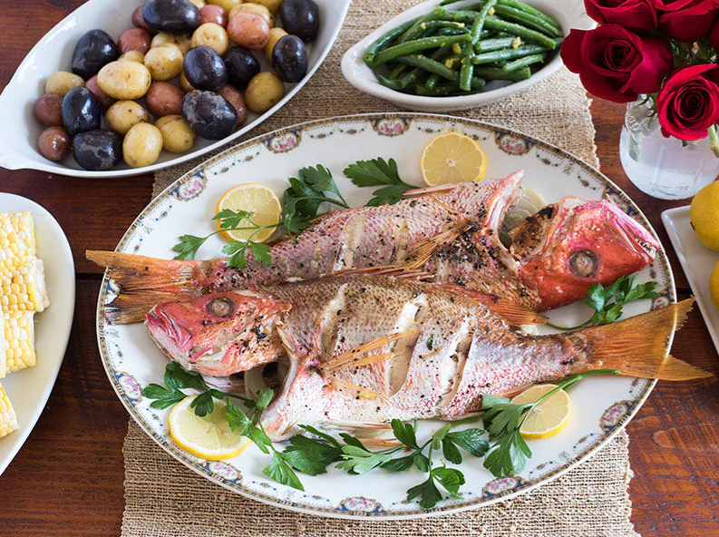 A plate of fish and vegetables on a table.