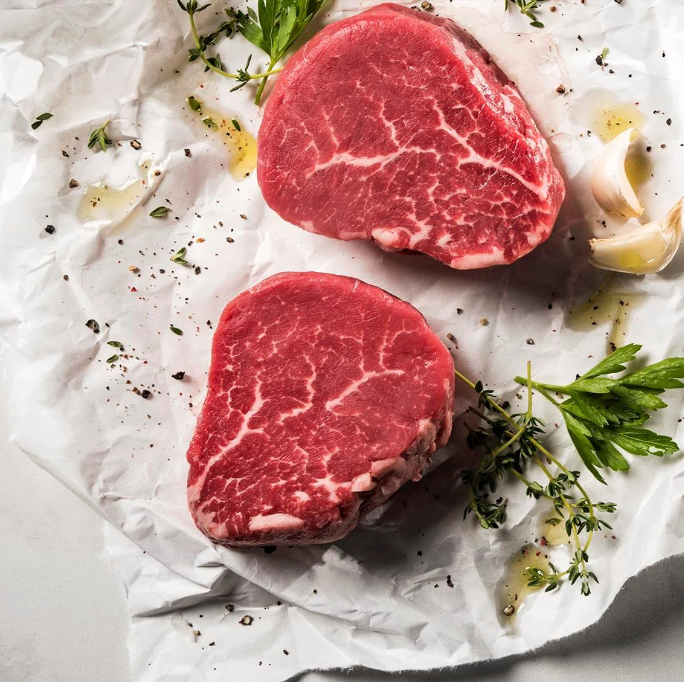 Two steaks are sitting on a piece of crumpled paper