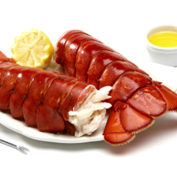A white plate topped with lobster tails and a slice of lemon