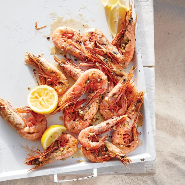 A tray of shrimp with lemon slices on top