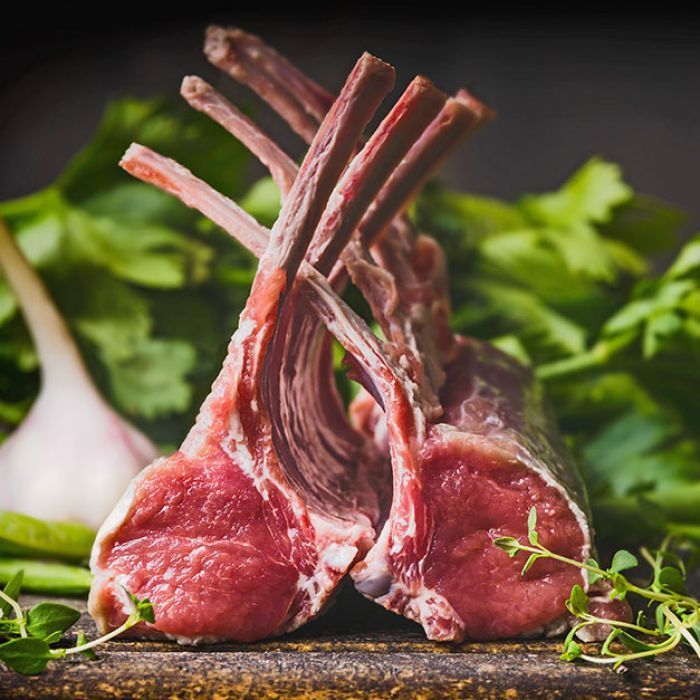 Two lamb chops are sitting on top of each other on a wooden table.