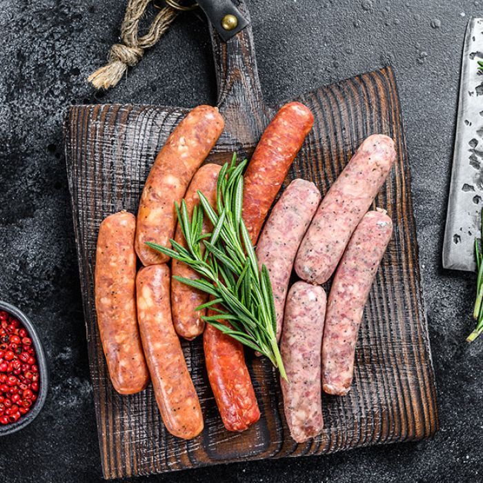 There are many different types of sausages on the cutting board.