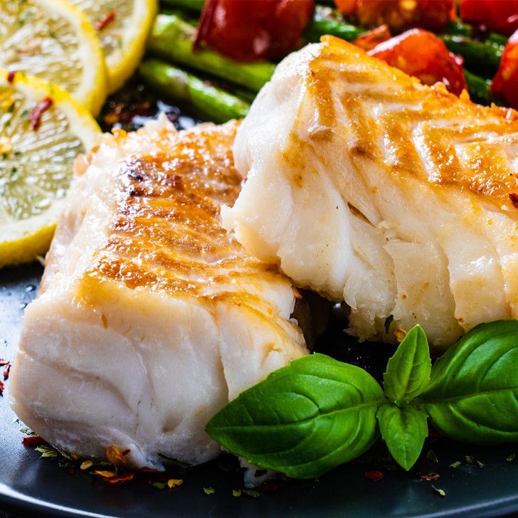 A close up of a plate of food with fish and vegetables on a table.