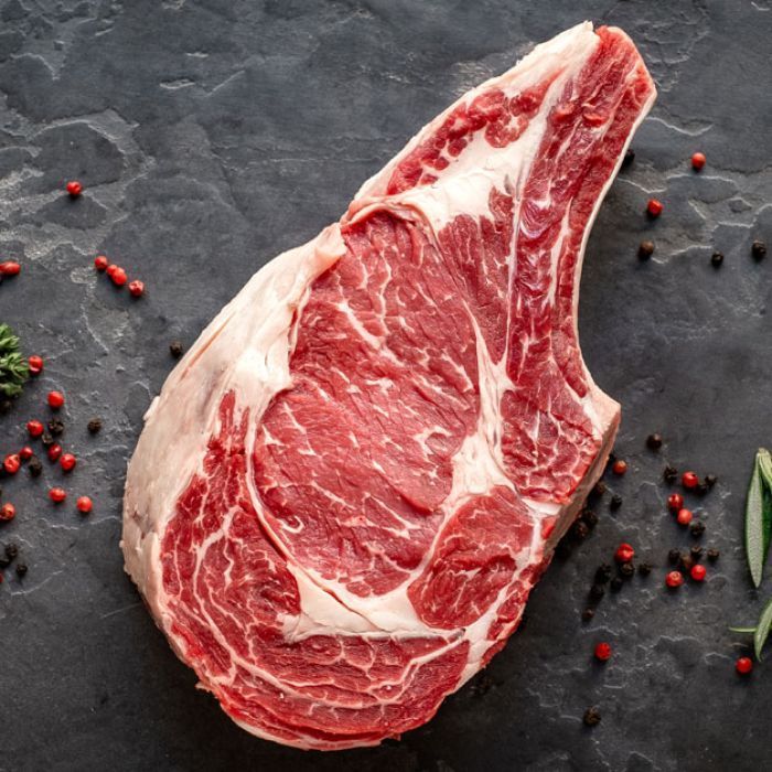 A large piece of raw beef is sitting on a table surrounded by spices.