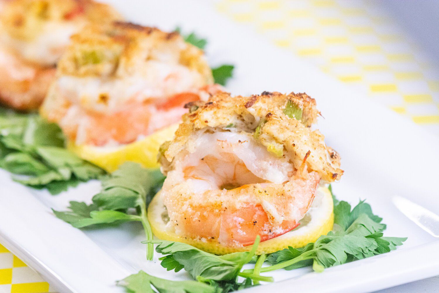 A close up of a plate of food with shrimp on a lemon slice.