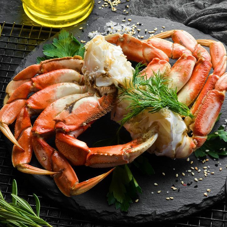 A crab is sitting on top of a black plate on a table.
