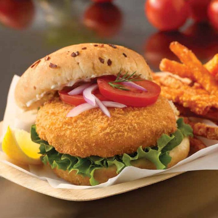 A fried chicken sandwich with lettuce tomato and onions