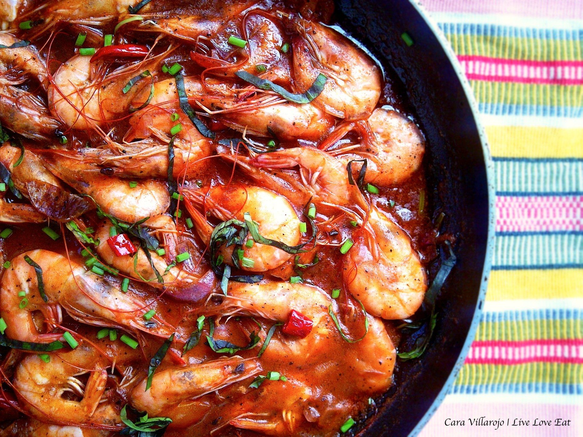 A pan filled with shrimp and sauce on a table