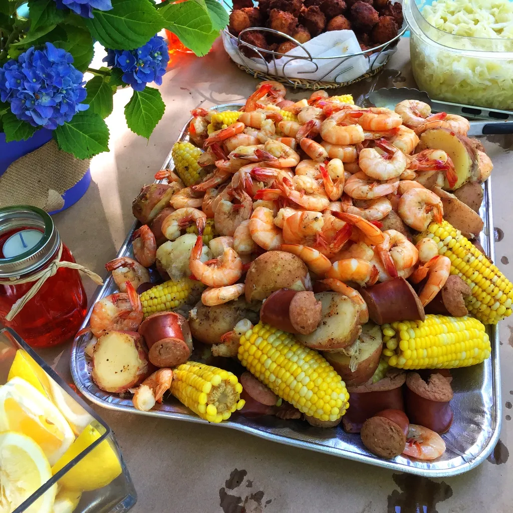 A tray of shrimp , corn , potatoes and sausage on a table.
