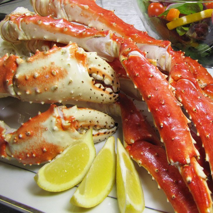 A pile of crab legs with lemon slices on a table