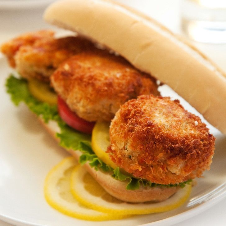 A close up of a sandwich with lettuce and lemon slices on a plate