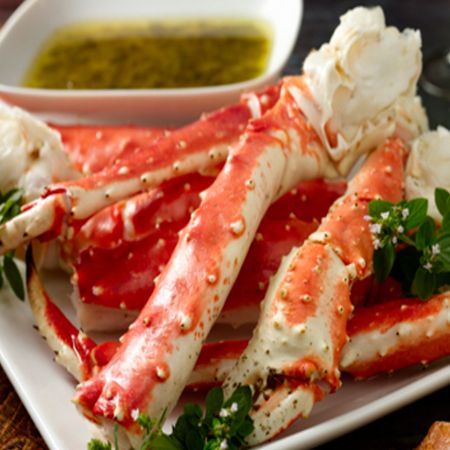 A white plate topped with crab legs and dipping sauce