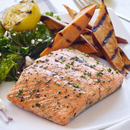 A white plate topped with a piece of salmon and sweet potato fries