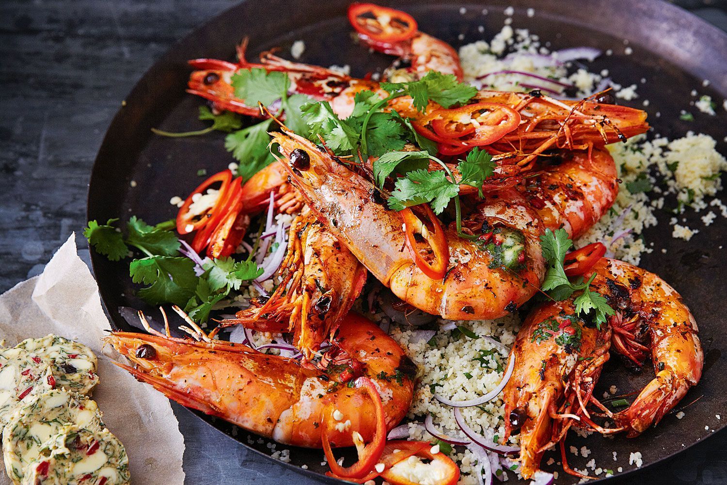 A pan filled with shrimp and vegetables on a table.