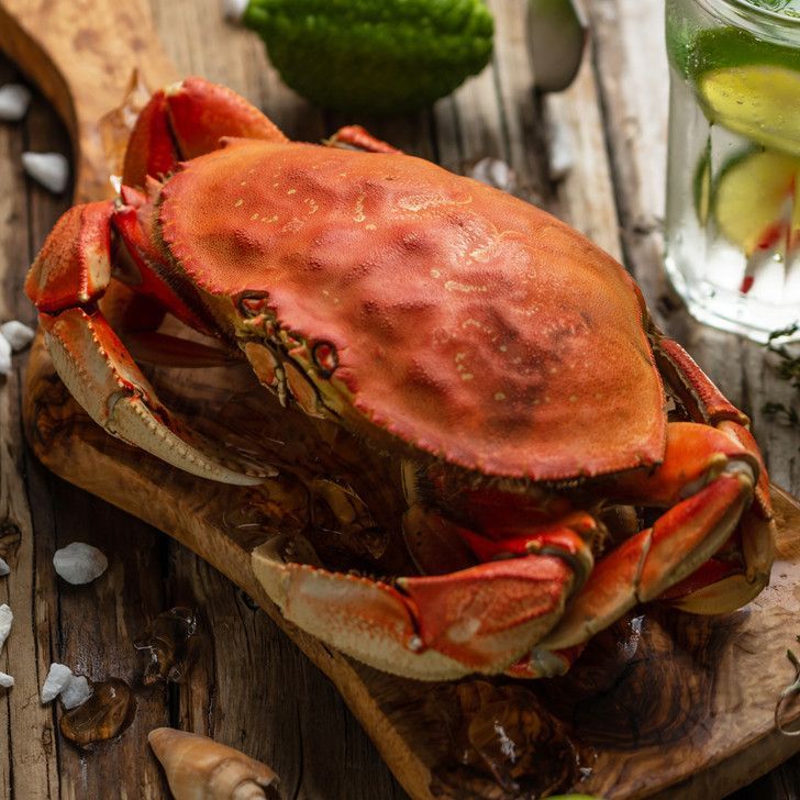 A large crab is sitting on a wooden cutting board