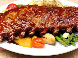 A white plate topped with ribs potatoes and asparagus