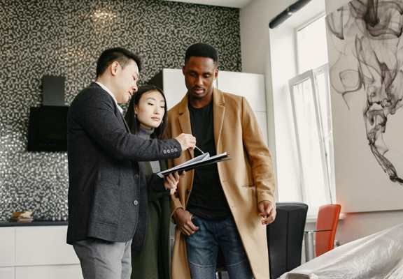 A man and a woman are looking at a clipboard in a living room.