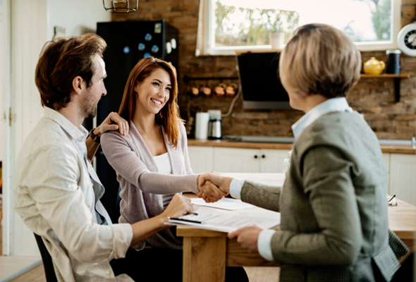 A man and woman are shaking hands with a woman while sitting at a table.