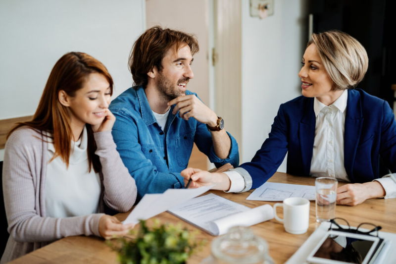 A man and a woman are sitting at a table talking to a woman.