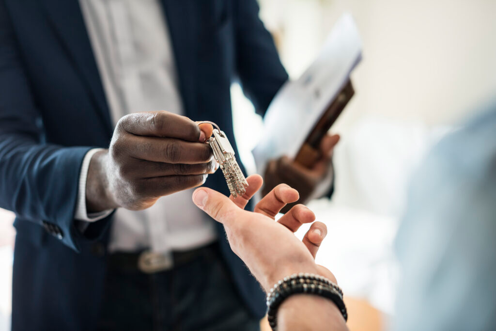 A man in a suit is handing a key to a woman.