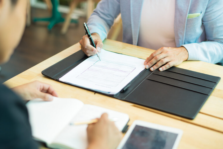 A man and a woman are sitting at a table signing a document.